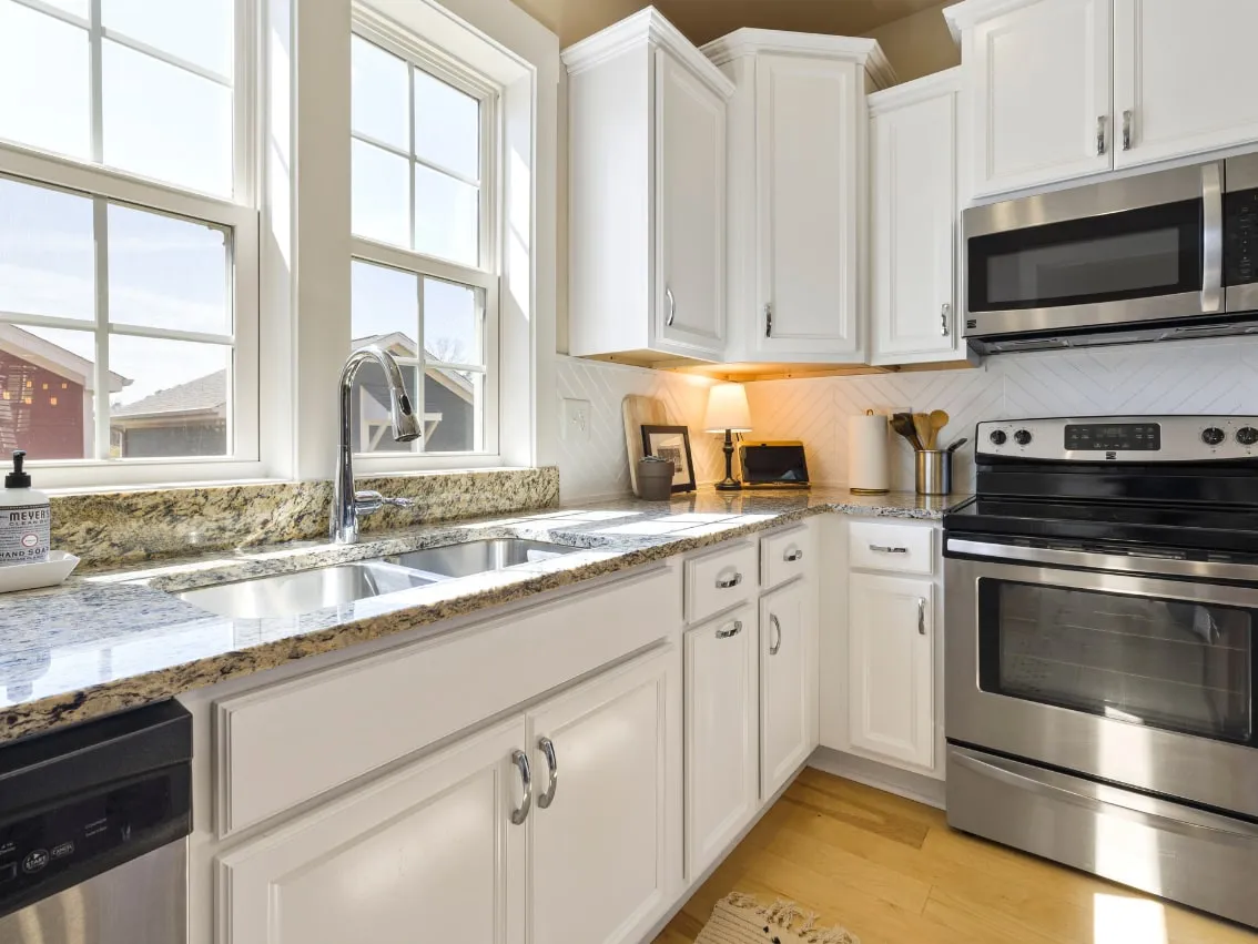 Clean white kitchen with polished countertops and stainless appliances
